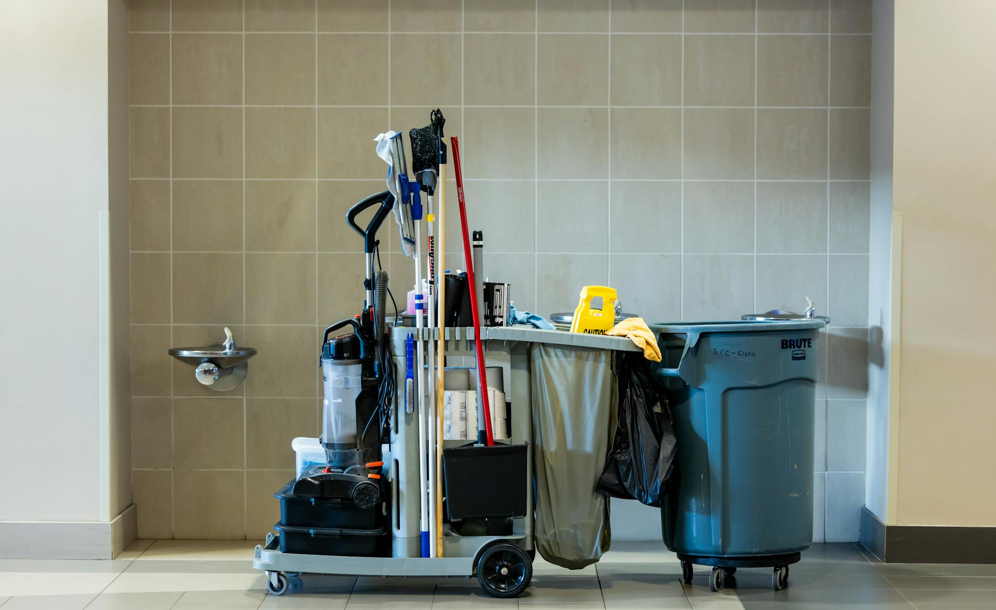 A comprehensive collection of professional cleaning tools on a cart in an indoor environment.